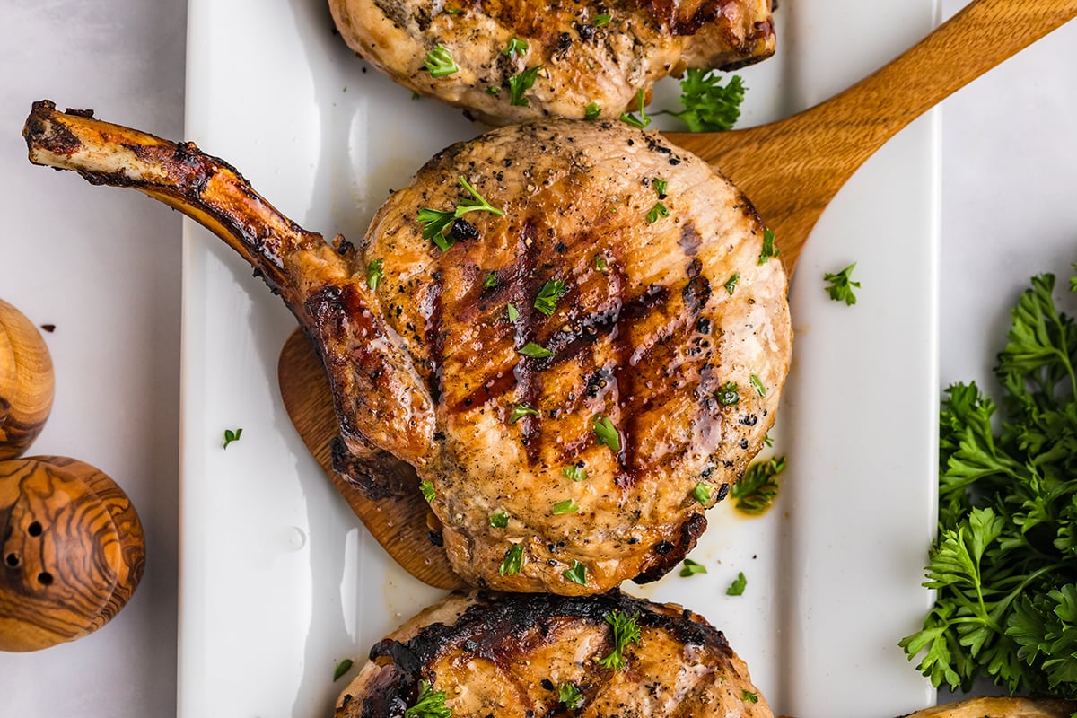 overhead shot of onion grilled pork chop on wooden spatula
