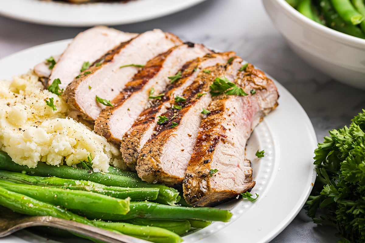 close up angled shot of sliced onion grilled pork chop on plate