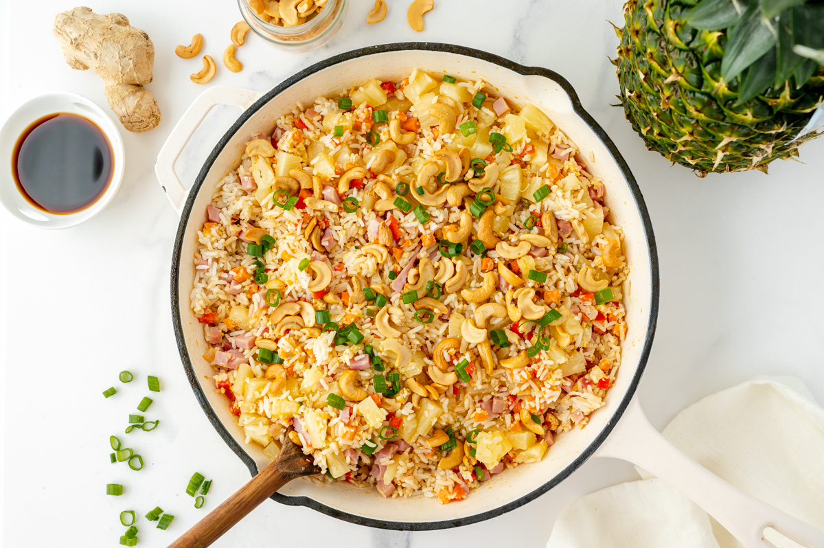 overhead shot of serving spoon in pan of fried rice with pineapple