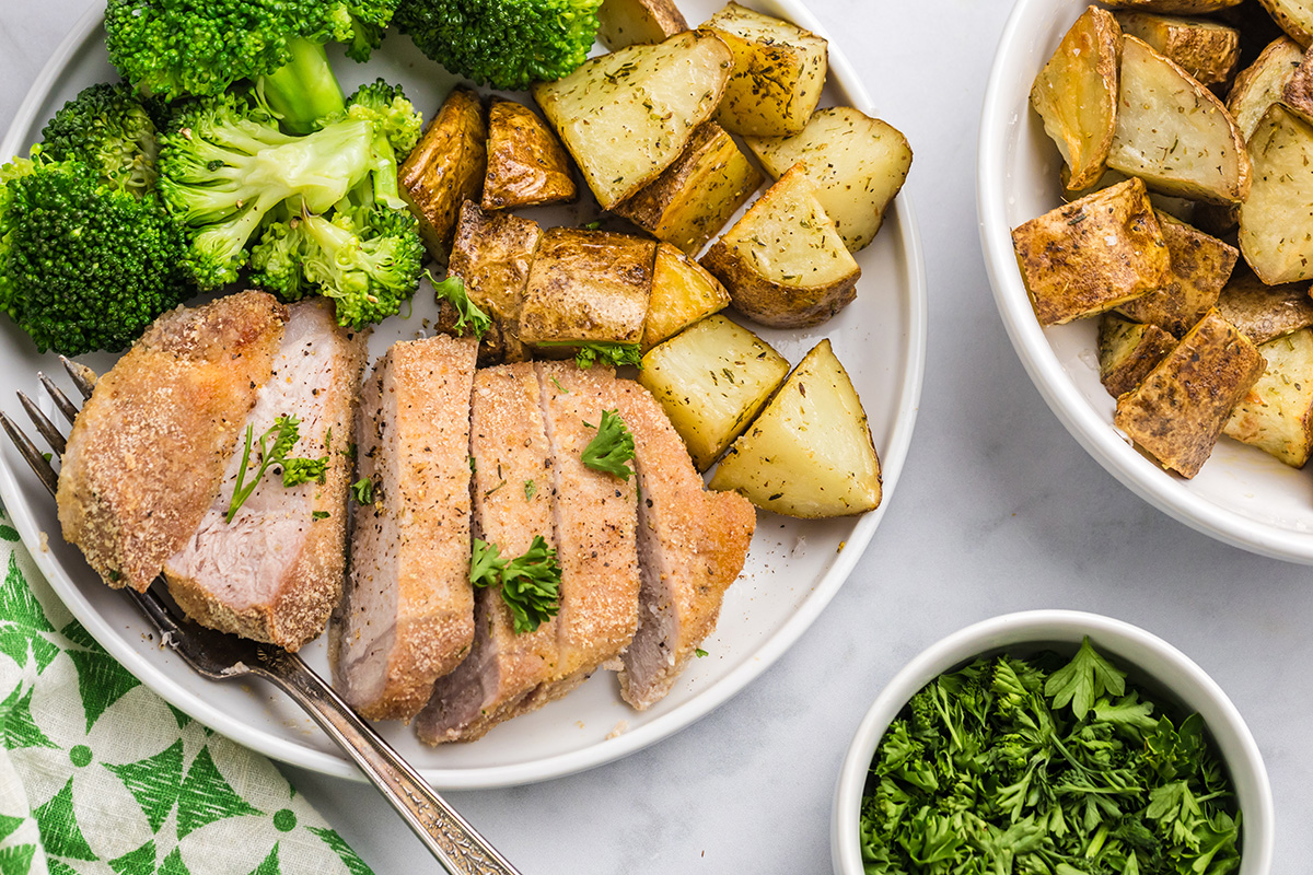 overhead shot of slice pork chop on plate with potatoes and broccoli