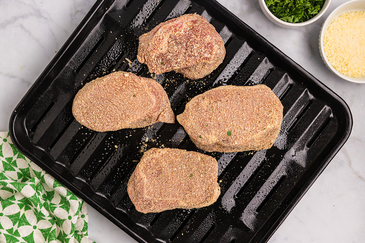 overhead shot of coated pork chops on pan