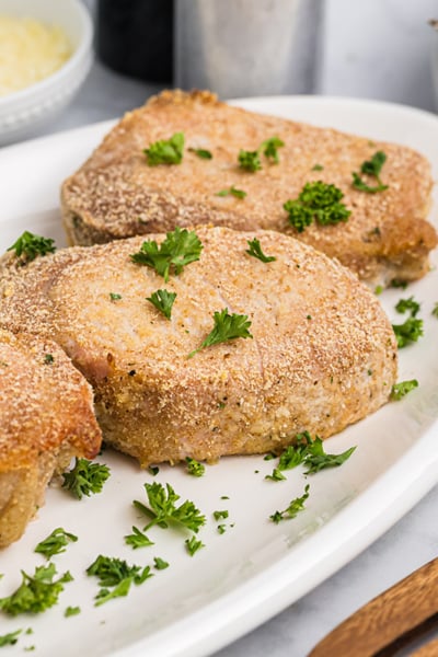 angled shot of four crispy pork chops on a platter