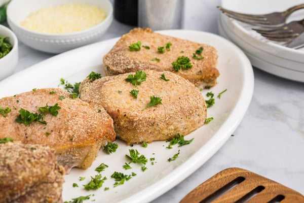 angled shot of four crispy pork chops on a platter