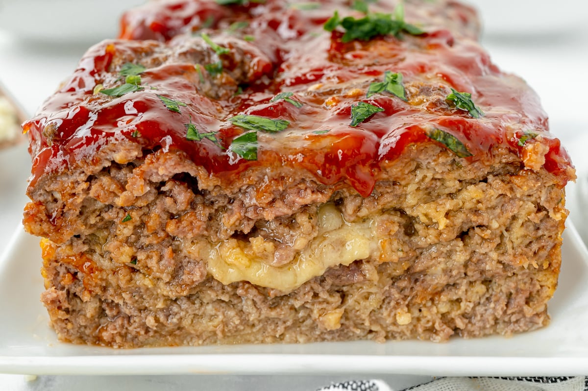 close up straight on shot of stuffed cheesy meatloaf on platter