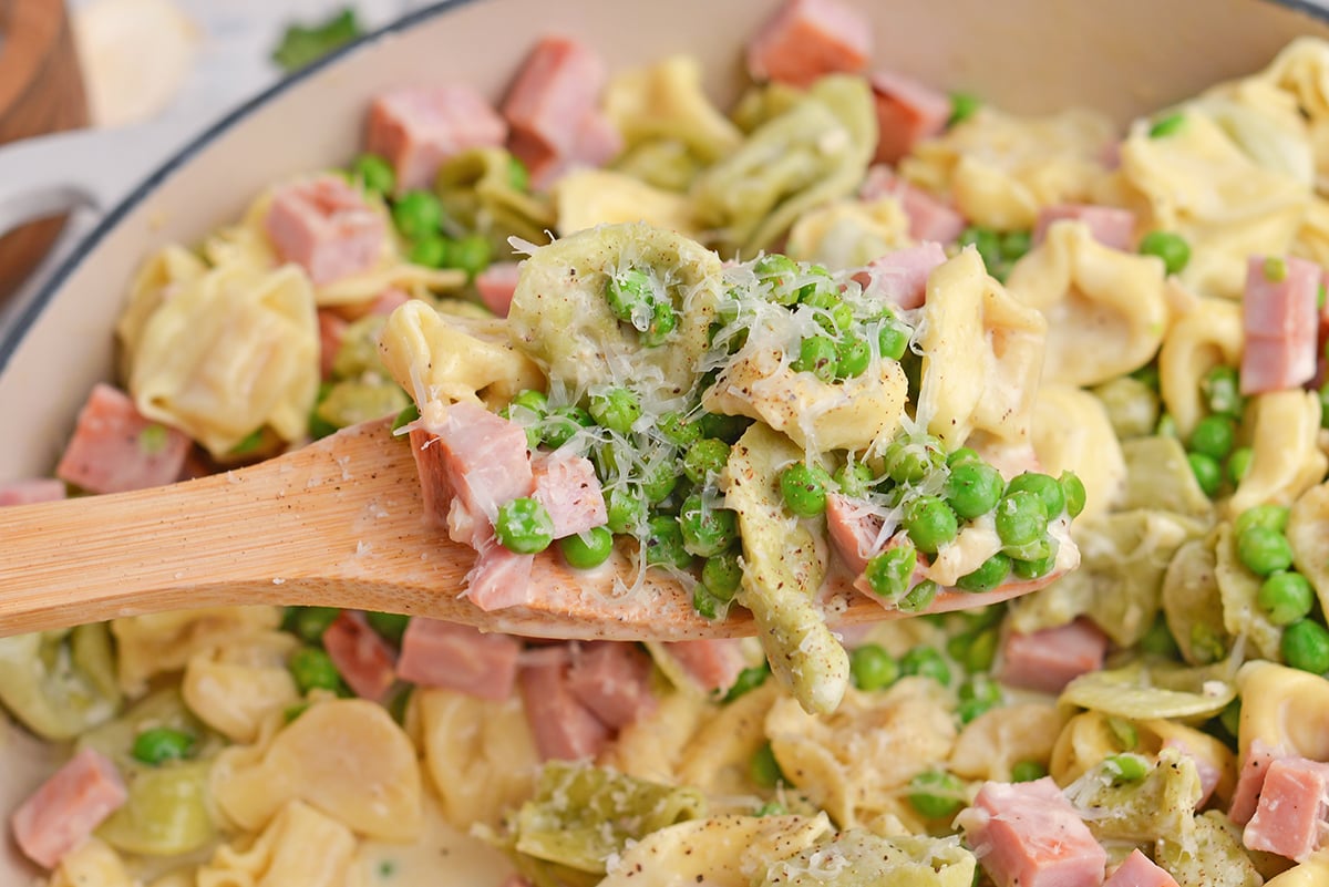 close up of ham and cheese tortellini on wooden spoon