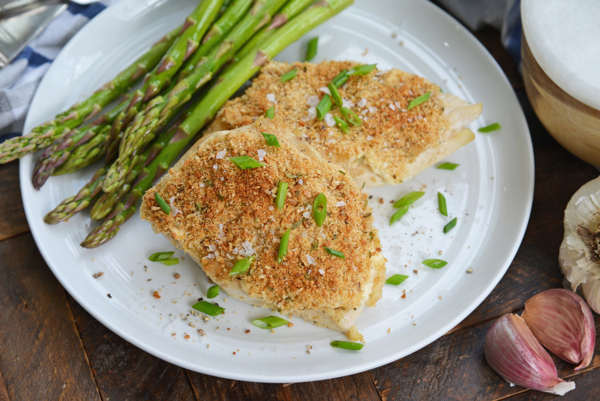 garlic parmesan chicken on a white plate with asparagus