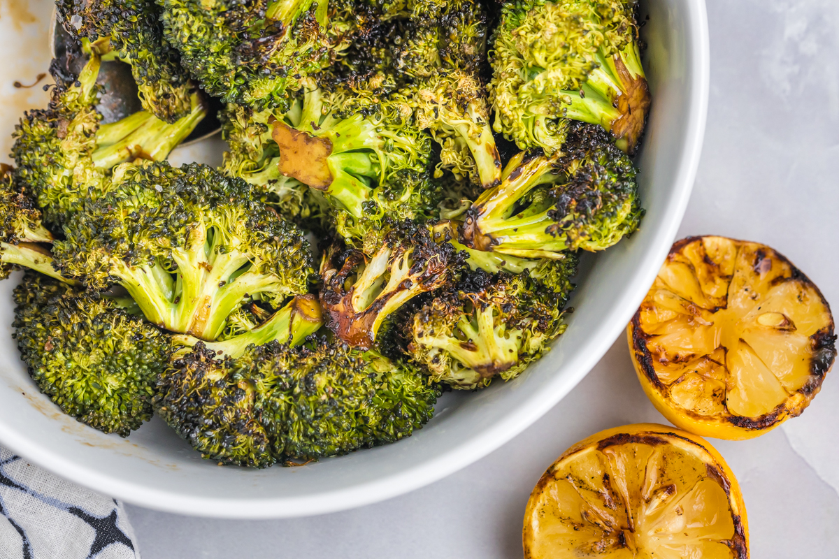 close up overhead shot of bowl of grilled broccoli with charred lemon