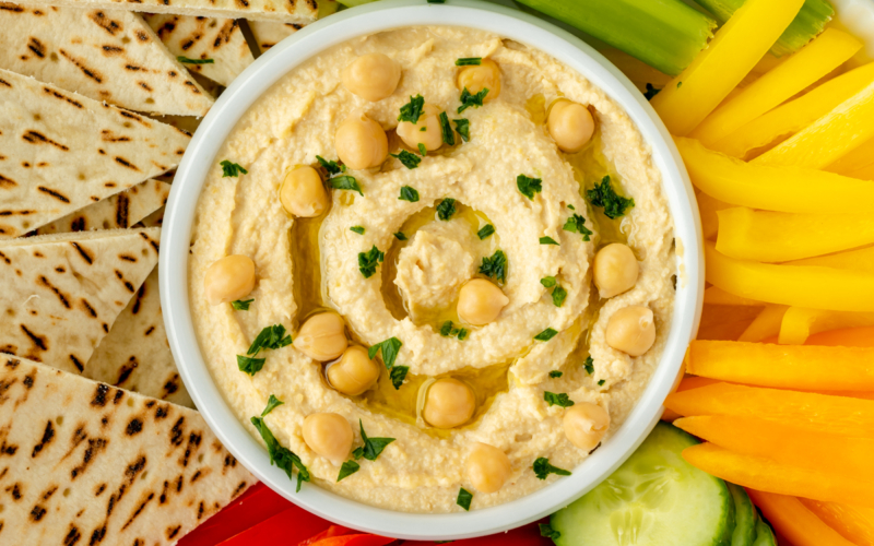 close up overhead shot of bowl of hummus with veggies
