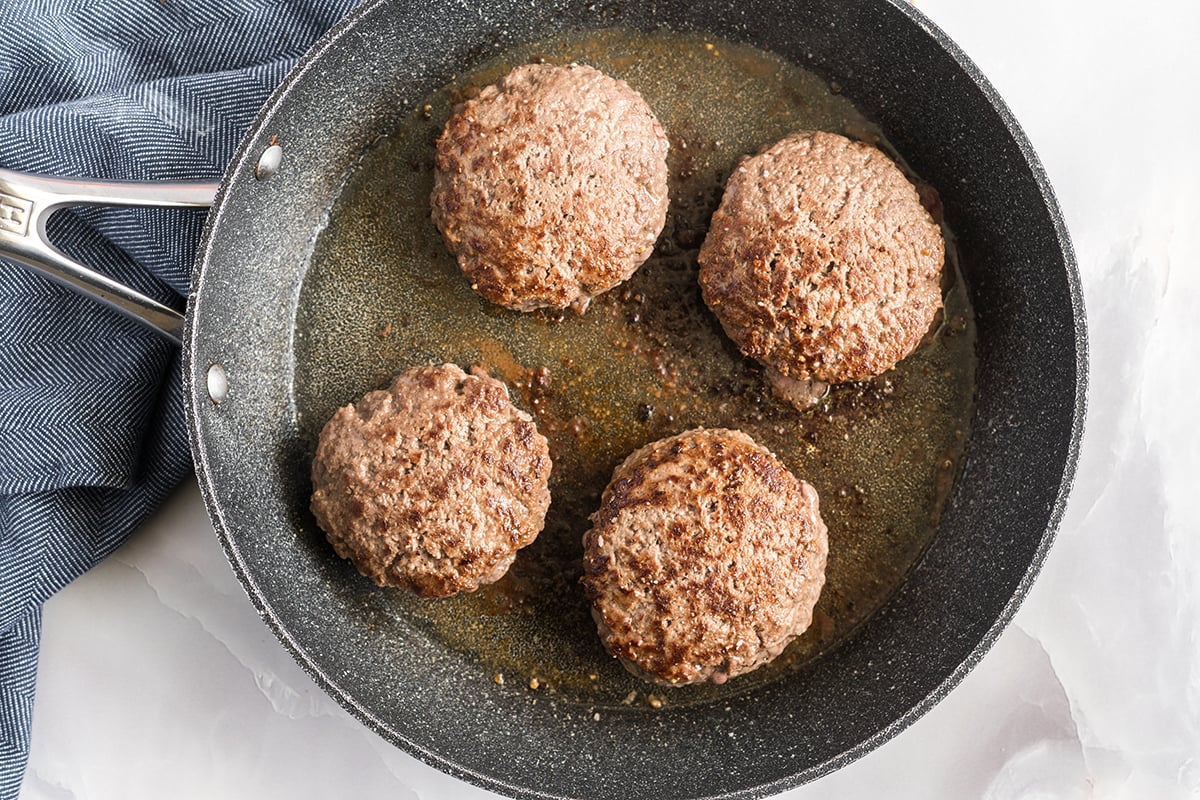 four cooked burger in pan