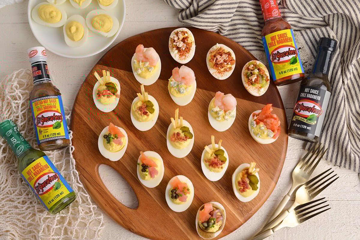 wide angle board of deviled eggs with hot sauce bottles