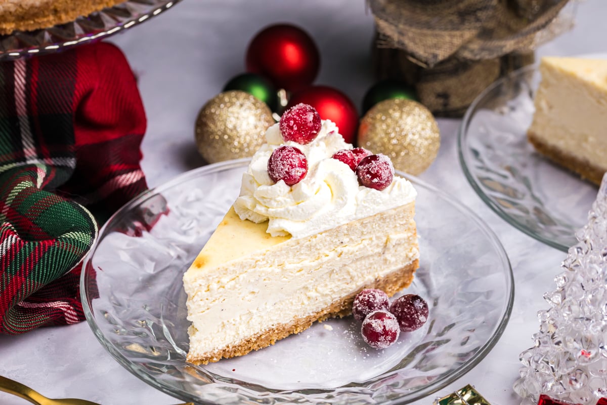 angled shot of slice of cheesecake on plate topped with sugared cranberries