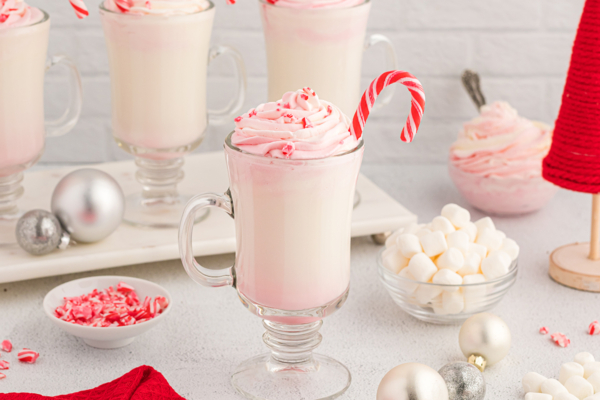 straight on shot of white hot chocolate topped with whipped cream with candy cane