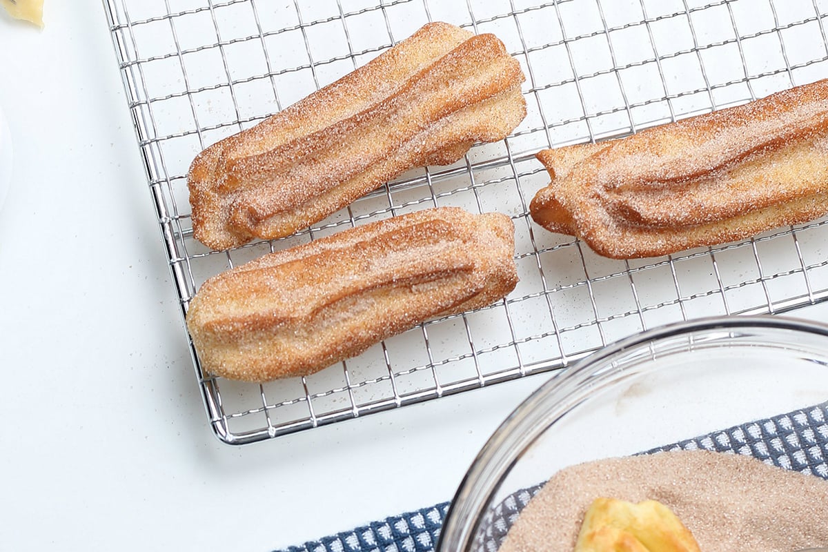 churros cooling after cinnamon sugar tossing