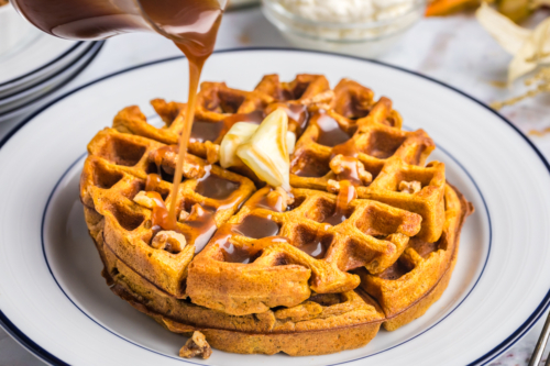syrup pouring over two pumpkin waffles