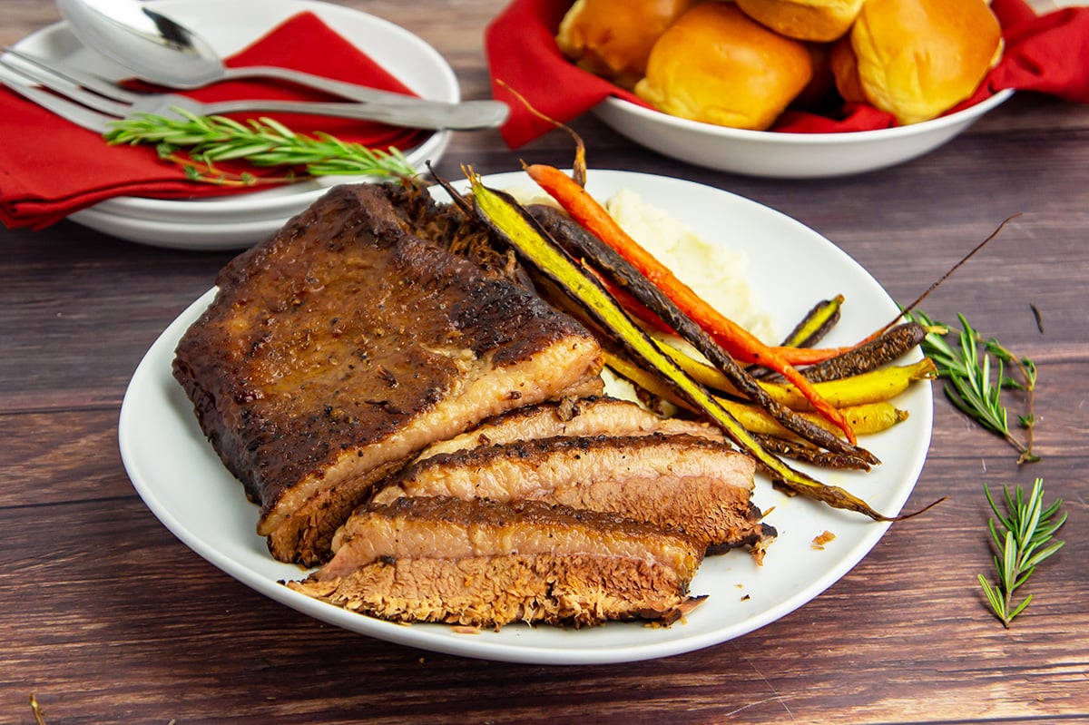 angled shot of sliced brisket on plate with carrots