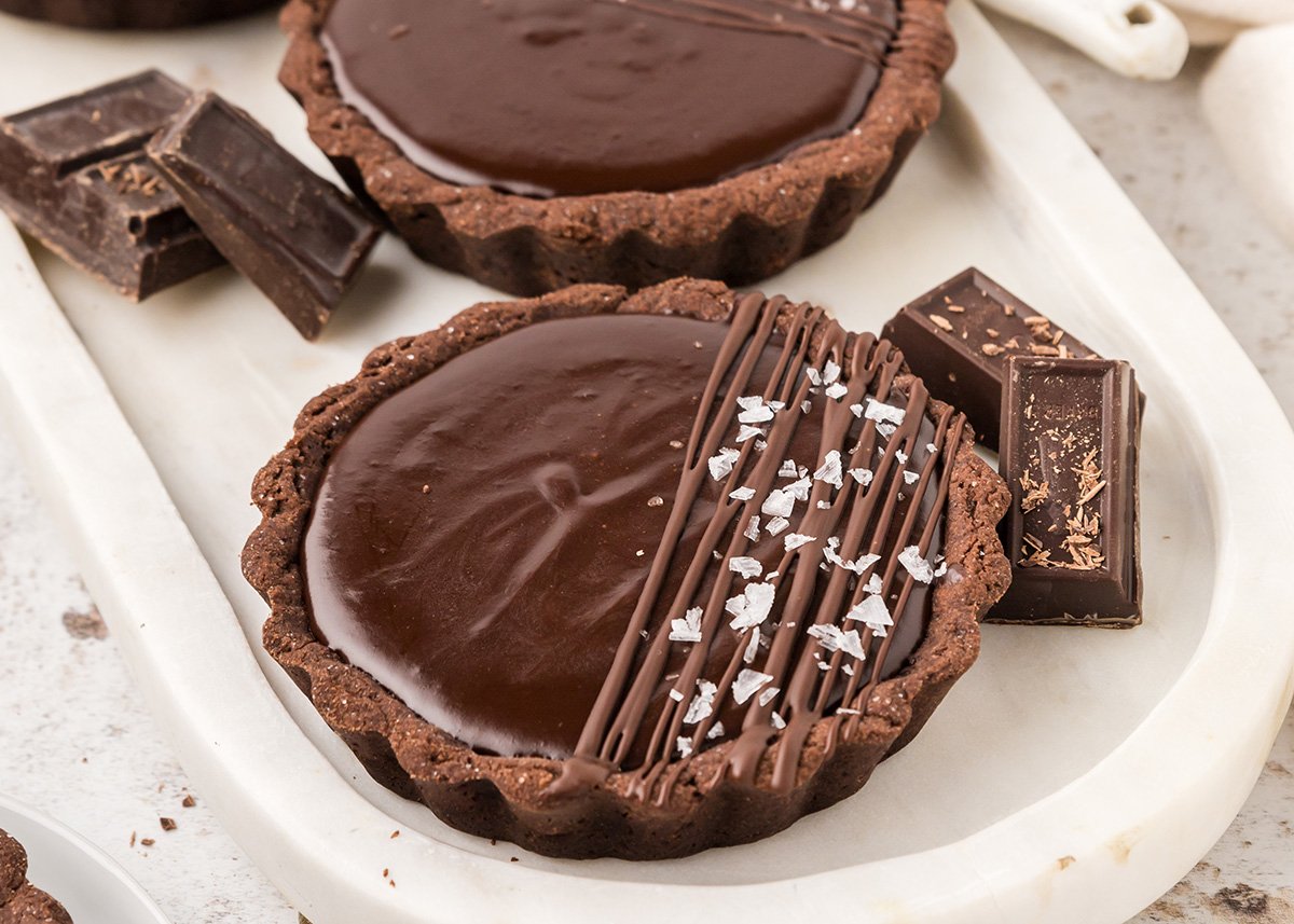 angled shot of sea salt sprinkled onto mini chocolate tart