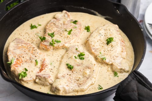 angled shot of skillet of creamy pork chops