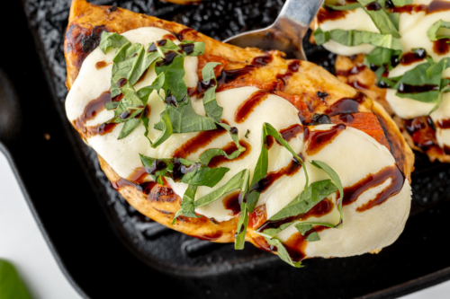overhead shot of spatula under caprese chicken on grill