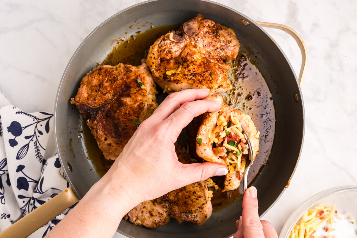 spoon adding cheese and bacon stuffing to pork chops