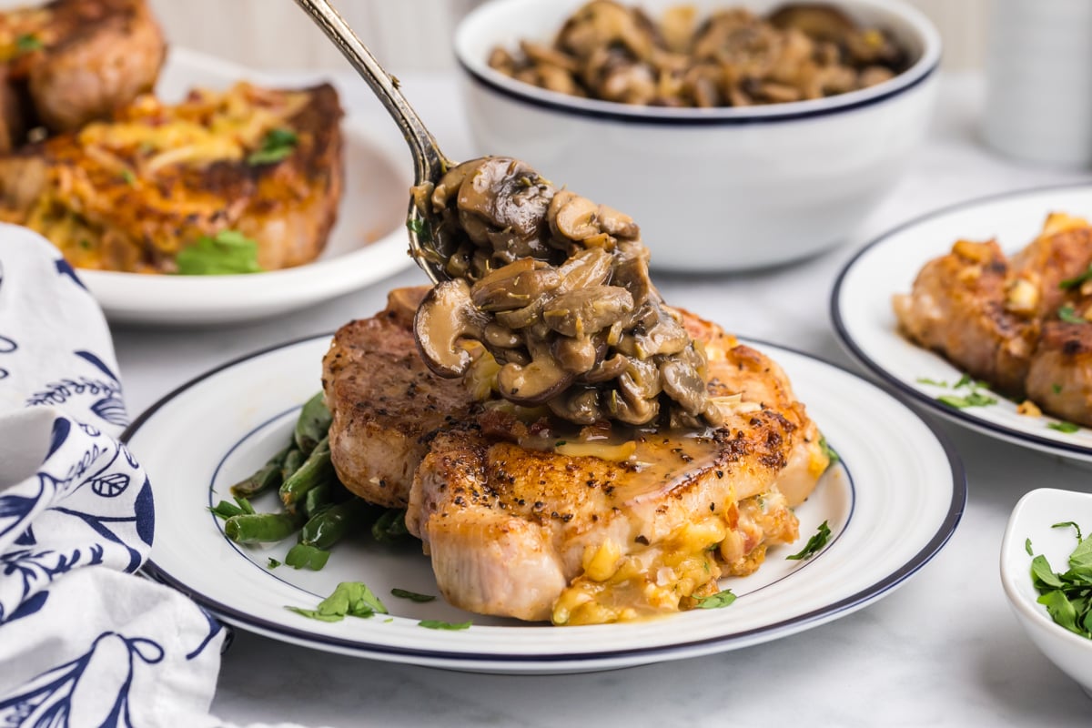 spoon adding mushrooms to pork chop