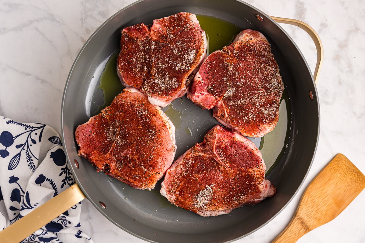 overhead shot of pork chops cooking in skillet