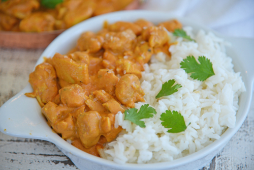 angled shot of bowl of butter chicken with rice