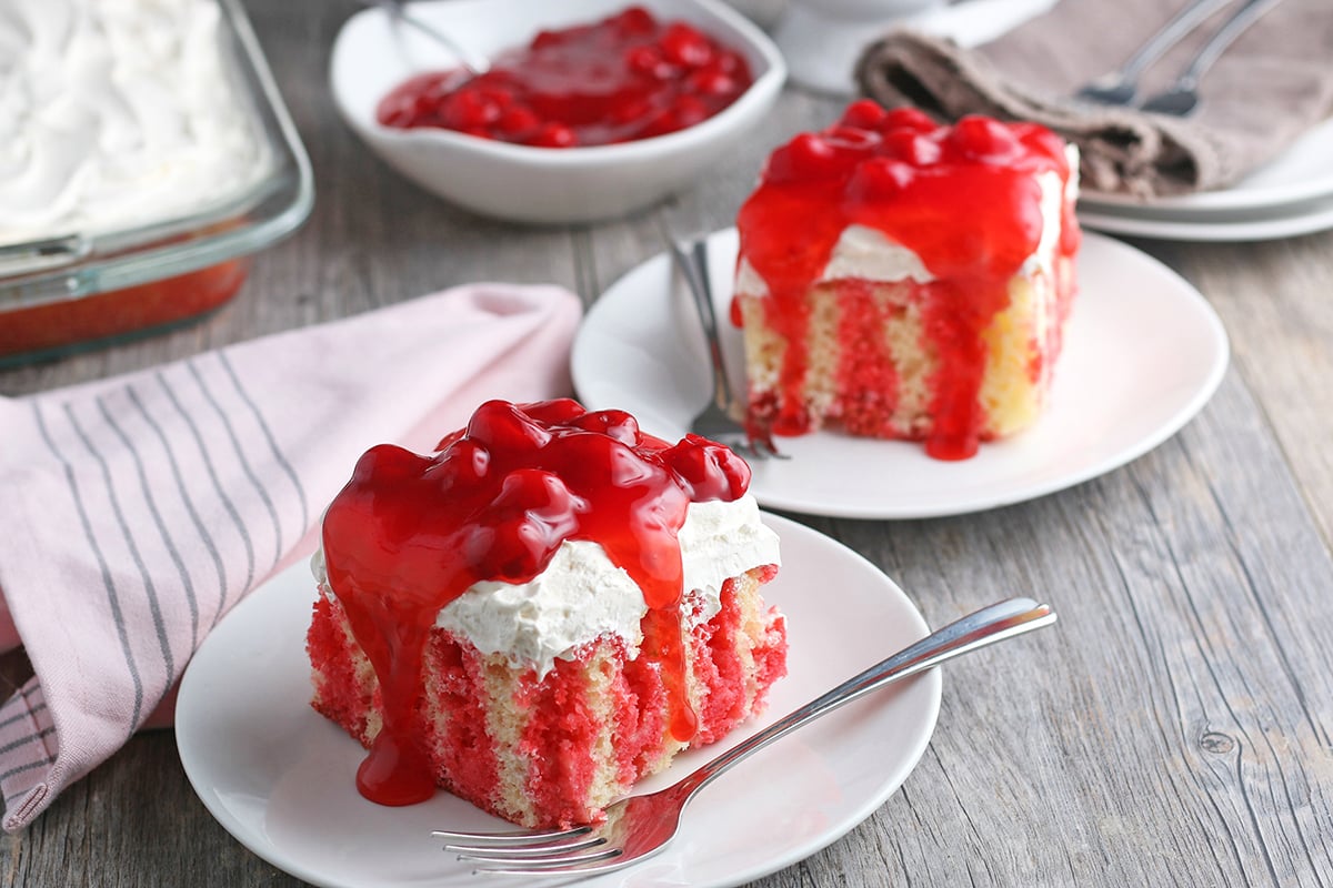 two slices of cherry poke cake on plates