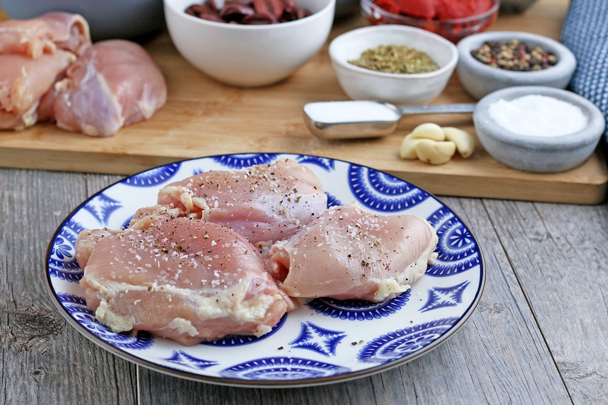 angled shot of seasoned raw chicken on plate