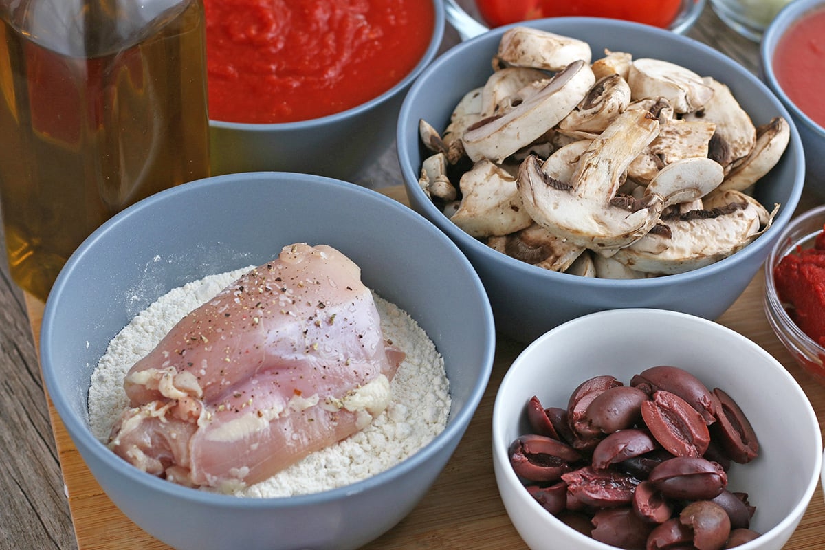angled shot of bowls of flour, mushrooms and olives