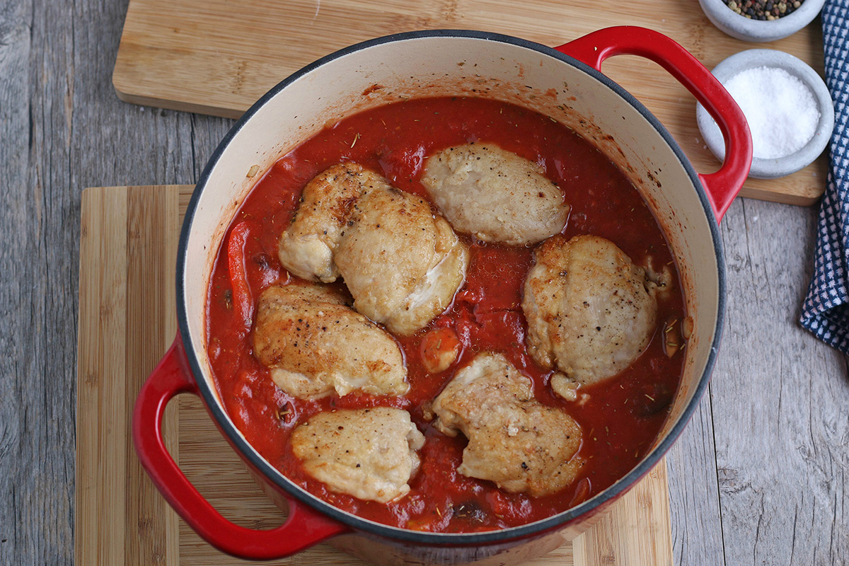 overhead shot of chicken cooking in sauce in dutch oven