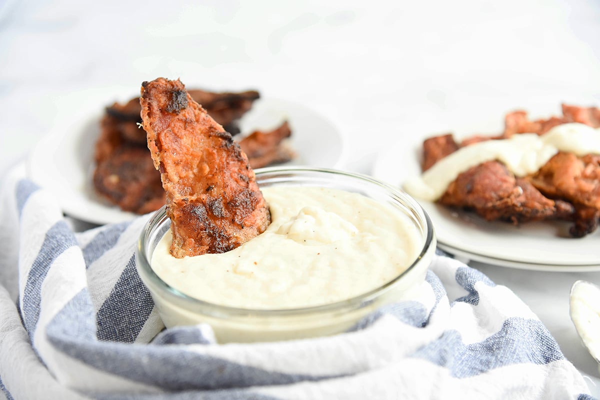 chicken fried bacon dipping in bowl of gravy