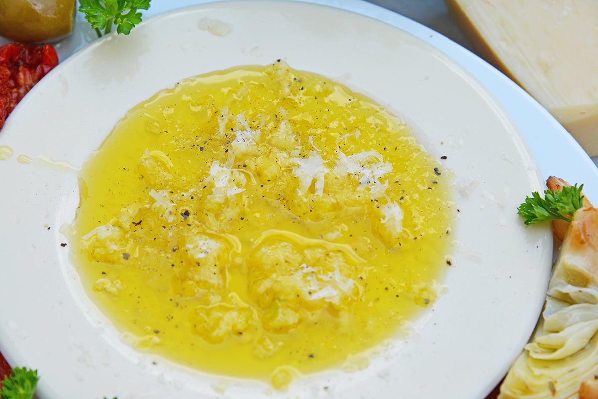 close up angled shot of plate of garlic parmesan olive oil bread dip