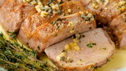 angled shot of sliced pork tenderloin medallions with garlic butter