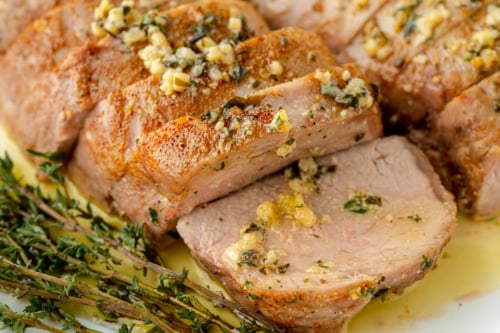angled shot of sliced pork tenderloin medallions with garlic butter