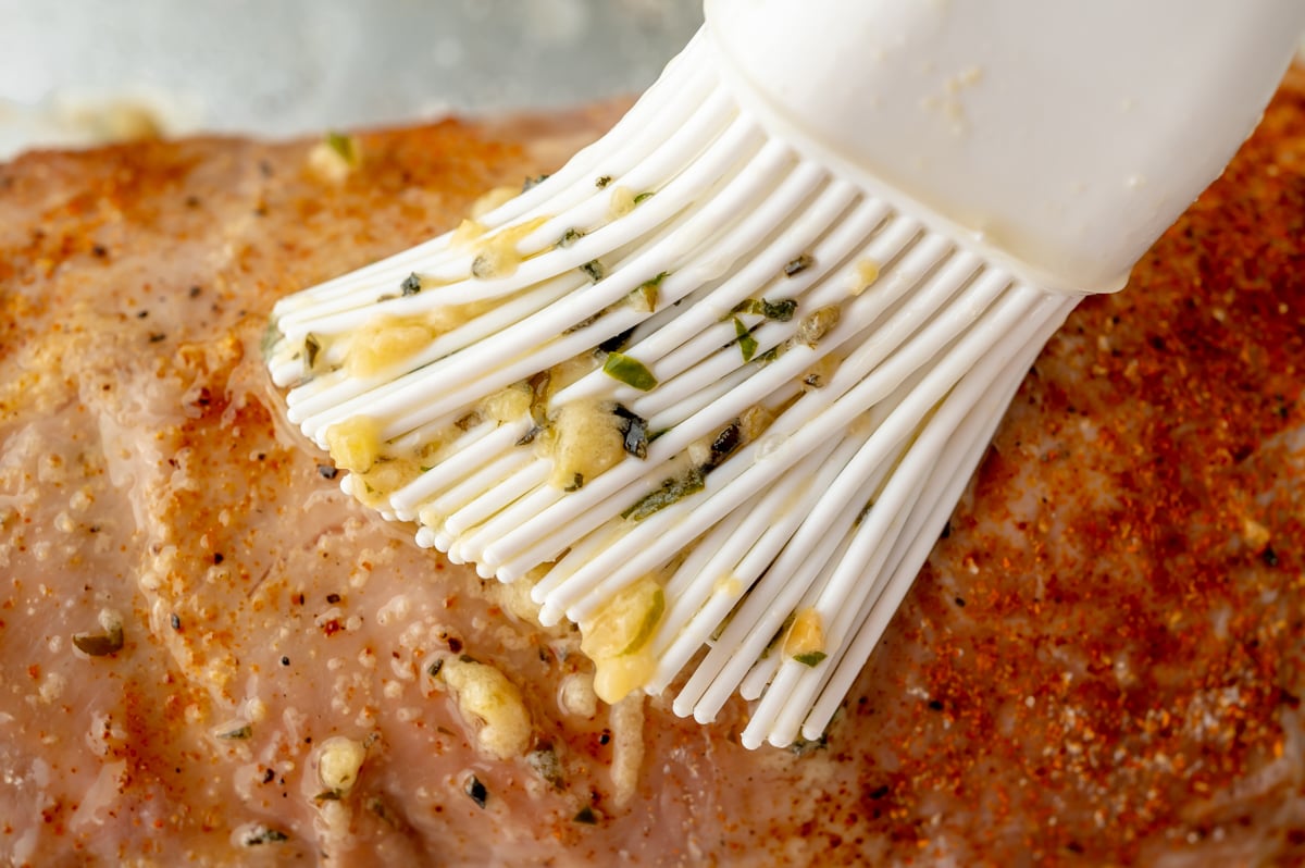 close up of garlic butter brushing onto pork tenderloin