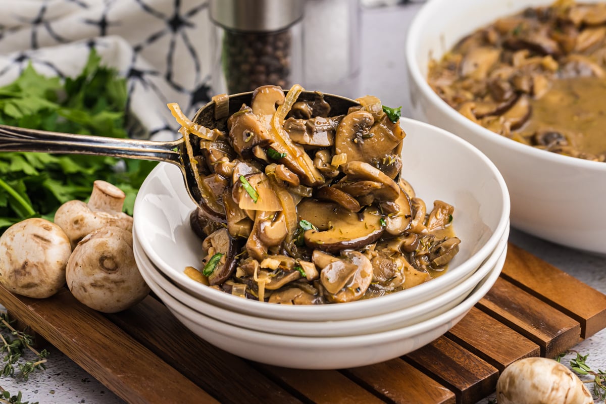 serving spoon adding mushrooms and onions to bowl