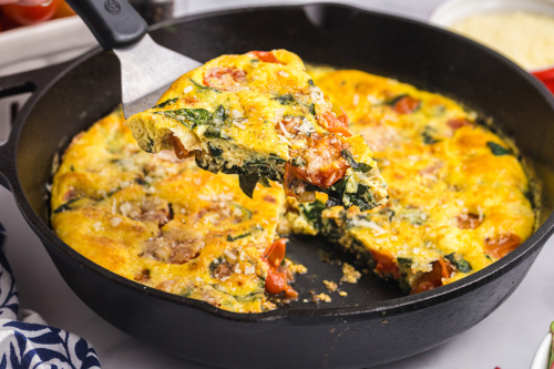 angled shot of slice of tomato spinach frittata on spatula
