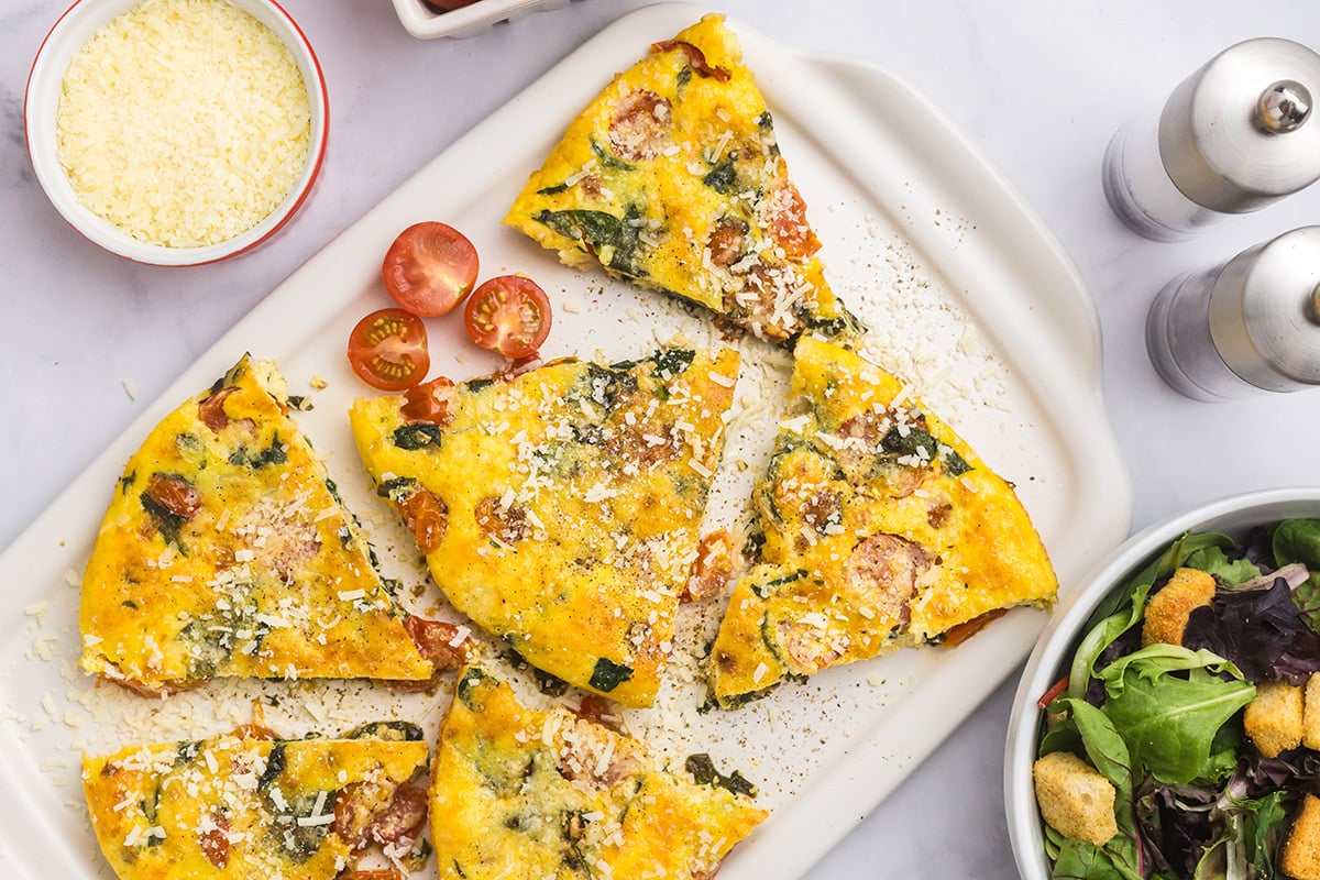 overhead shot of platter of slices of tomato spinach frittata
