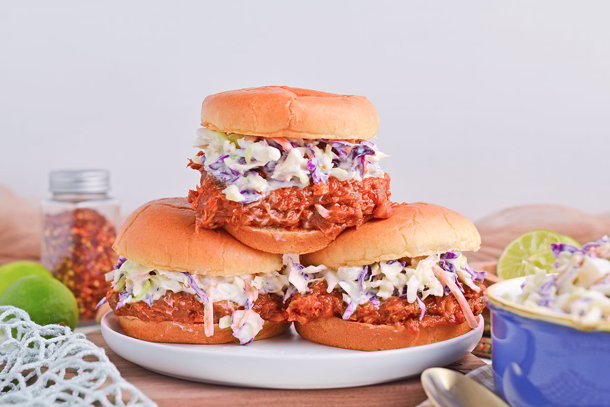 straight on shot of three pulled pork sandwiches topped with coleslaw