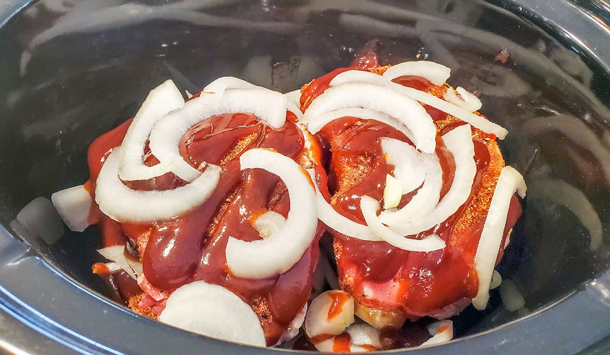 pork in crock pot with onions and sauce