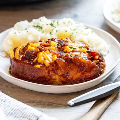 angled shot of crock pot pork chop on plate with potatoes