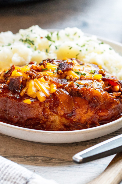 angled shot of crock pot pork chop on plate with potatoes