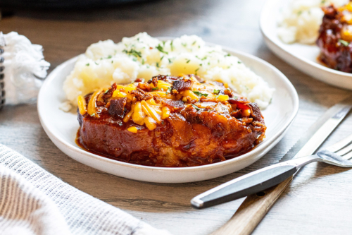 angled shot of crock pot pork chop on plate with potatoes