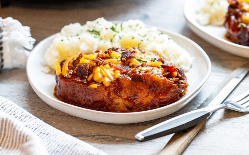 angled shot of crock pot pork chop on plate with potatoes