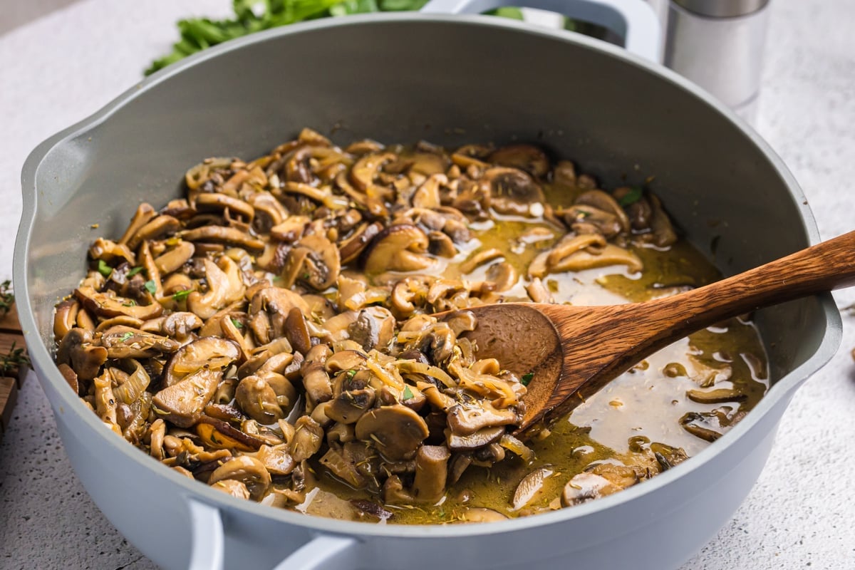 angled shot of wooden spoon in pan of mushrooms