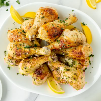 overhead shot of baked chicken drumsticks on platter with lemon wedges