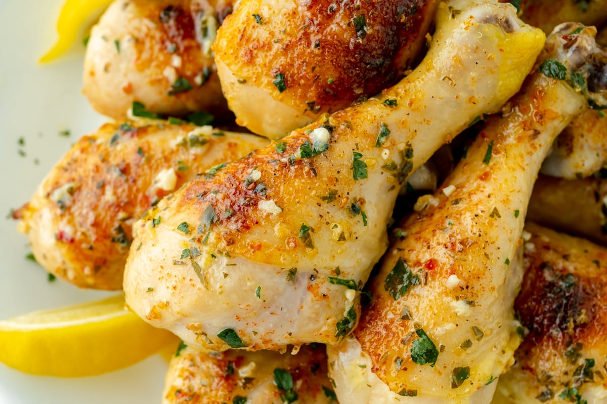 close up overhead shot of baked chicken drumsticks with lemon wedges
