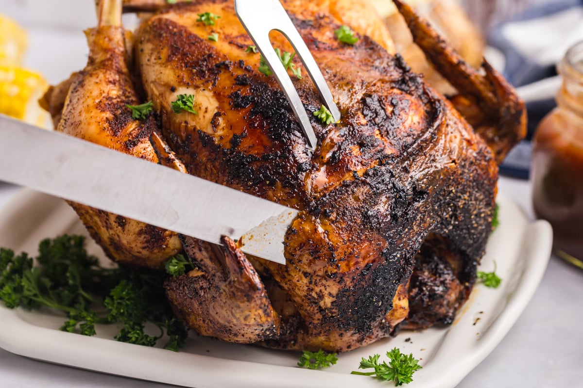 close up of knife cutting into beer can chicken on platter