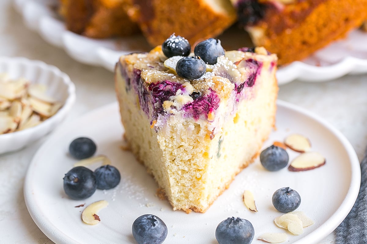 angled shot of bite taken out of slice of blueberry cream cheese coffee cake
