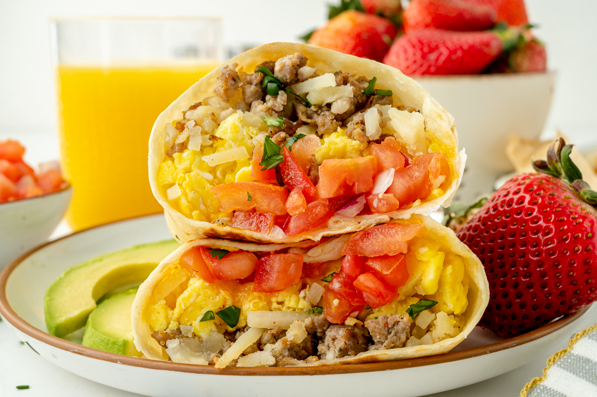 straight on shot of two breakfast burrito halves on plate with strawberry